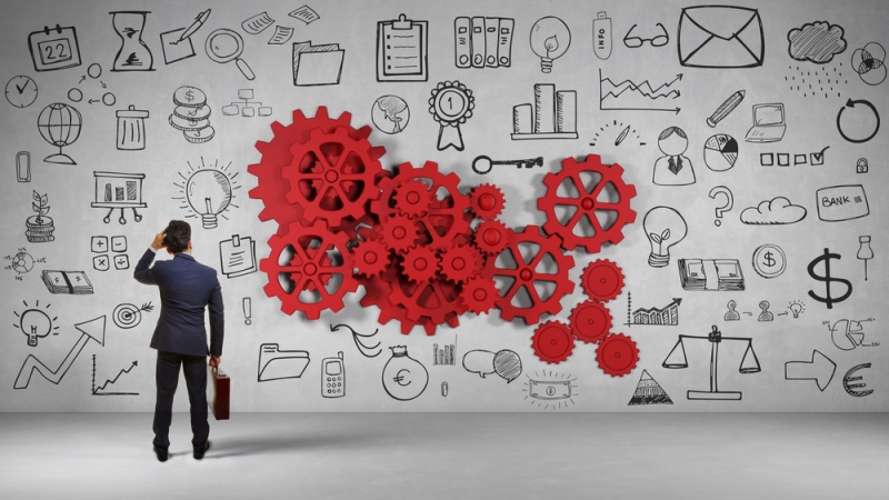 A Professional Business Man Standing infront of a big wall with full of business diagrams.