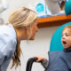 A female dentist asking to open the mouth of a girl child to check for any defects