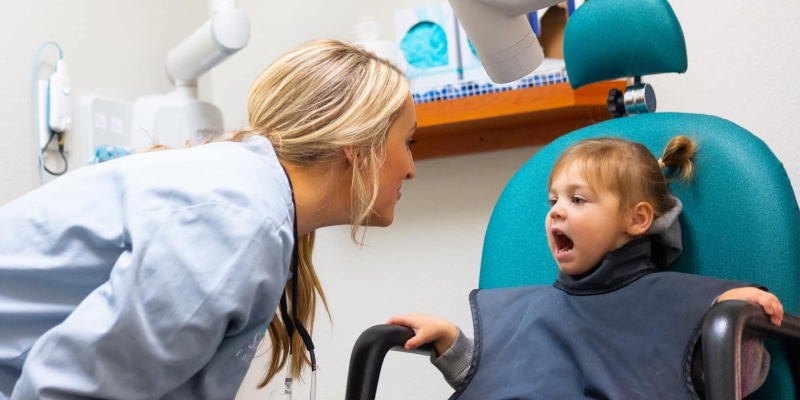 A female dentist asking to open the mouth of a girl child to check for any defects