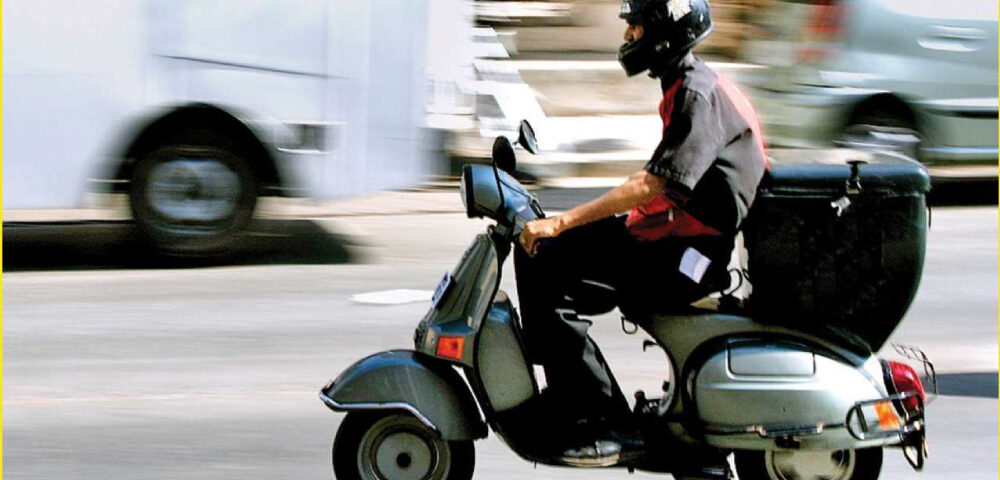 A delivery agent on his way to delivery on a two wheeler.