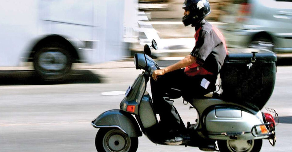 A delivery agent on his way to delivery on a two wheeler.